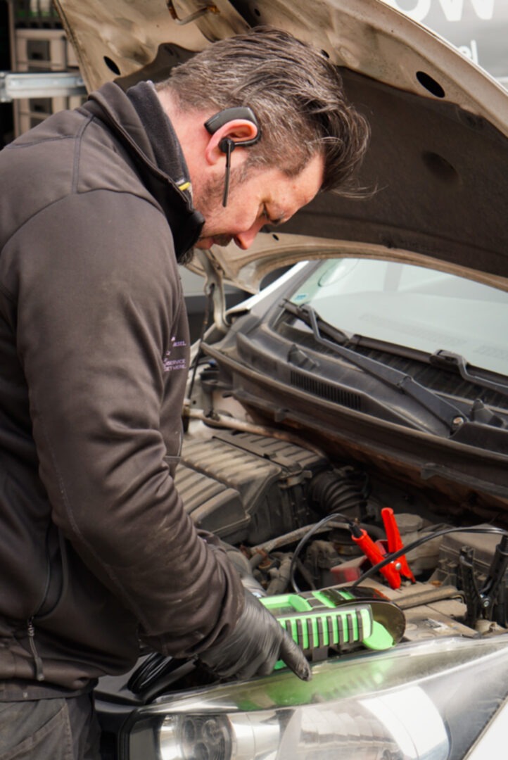 Mekaniker tester bilens batteri med en professionel batteritester i motorrummet.